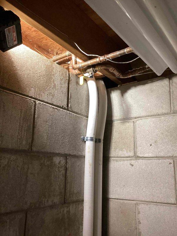 Responded to irrigation system leak involving broken piping in both exterior and interior locations. Inspected outdoor plumbing assembly featuring white PVC connected to multiple metal valves and fittings with blue-handled control valve, mounted against building exterior at grade level. Traced system through basement utility area where vertical white PVC pipe connects to horizontal copper supply lines at ceiling joists. Identified compromised pipe sections in the unusual configuration requiring replacement. Documented damage and provided part order form for estimate to repair broken pipes in both locations.