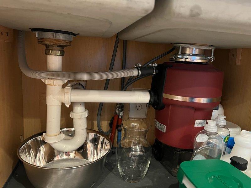 Removed existing garbage disposal unit from kitchen sink due to leaking drain assembly. Disconnected electrical wiring and detached disposal from mounting flange. Reconfigured drain plumbing by installing two new basket strainers to accommodate dual sink basins. Replaced deteriorated PVC drain pipes and fittings, including P-trap assembly, to eliminate leaks and ensure proper drainage. Reconnected dishwasher drain line to new drain configuration and verified all connections are secure and leak-free.