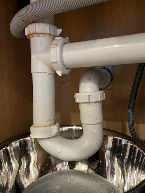 Removed existing garbage disposal unit from kitchen sink due to leaking drain assembly. Disconnected electrical wiring and detached disposal from mounting flange. Reconfigured drain plumbing by installing two new basket strainers to accommodate dual sink basins. Replaced deteriorated PVC drain pipes and fittings, including P-trap assembly, to eliminate leaks and ensure proper drainage. Reconnected dishwasher drain line to new drain configuration and verified all connections are secure and leak-free.