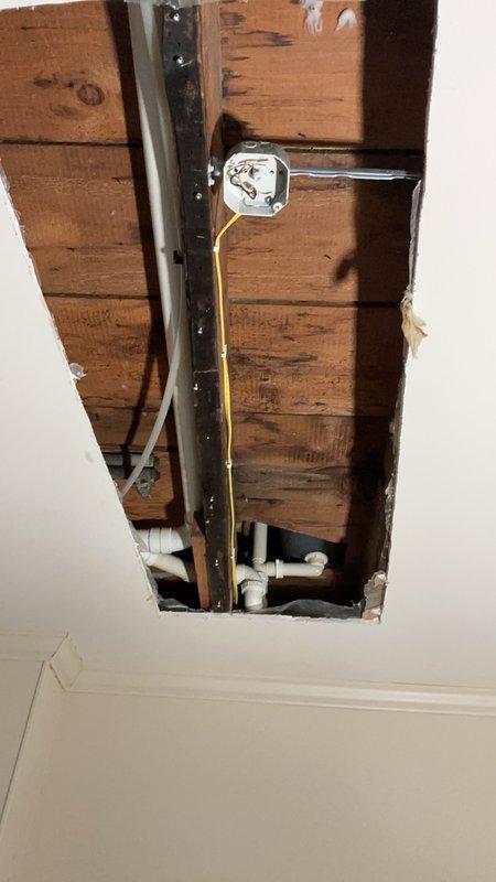 Responded to water leak originating from upstairs bathroom and penetrating through ceiling to lower level via exhaust fan opening. Conducted thorough inspection of upstairs bathroom including bathtub-shower combination with tile surround to identify source of water intrusion. Created ceiling access opening in lower level to trace leak path and examine plumbing infrastructure, revealing that water was infiltrating through compromised tile in the upstairs bathroom floor and migrating through structural framing to the level below.