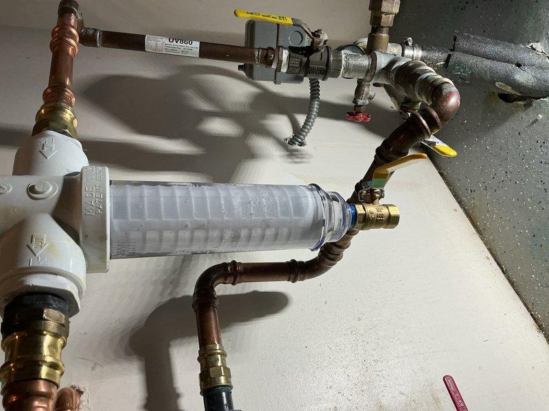 Responded to a water leak at the Rusco filter assembly that developed following a previous filter replacement. Upon inspection, identified a small leak at the ball valve connection located below the Rusco filter housing. The issue was caused by insufficient tightening of the ball valve during the prior service. Tightened down the ball valve to proper torque specifications, eliminating the leak. Verified all connections at the clear cylindrical filter housing and associated copper piping with brass fittings for proper seal integrity. System tested and confirmed leak-free operation.
