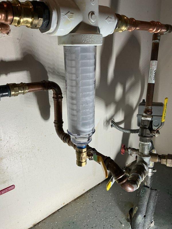 Responded to a water leak at the Rusco filter assembly that developed following a previous filter replacement. Upon inspection, identified a small leak at the ball valve connection located below the Rusco filter housing. The issue was caused by insufficient tightening of the ball valve during the prior service. Tightened down the ball valve to proper torque specifications, eliminating the leak. Verified all connections at the clear cylindrical filter housing and associated copper piping with brass fittings for proper seal integrity. System tested and confirmed leak-free operation.