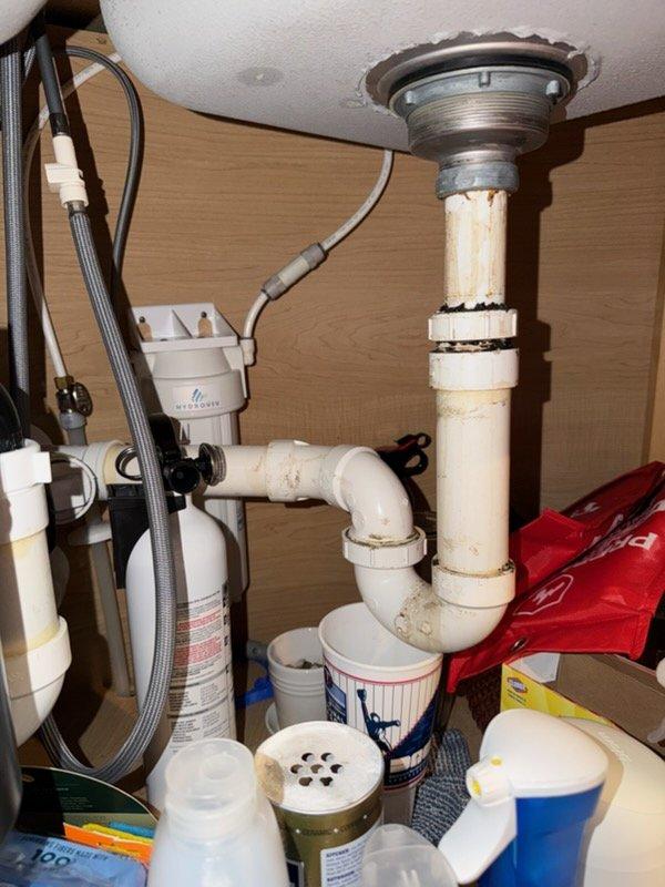 Completed kitchen sink installation following new countertop installation. Installed new faucet, garbage disposal unit, and complete drain assembly with P-trap configuration using PVC piping. Reconnected water supply lines to existing plumbing infrastructure and ensured all connections were secure and leak-free.