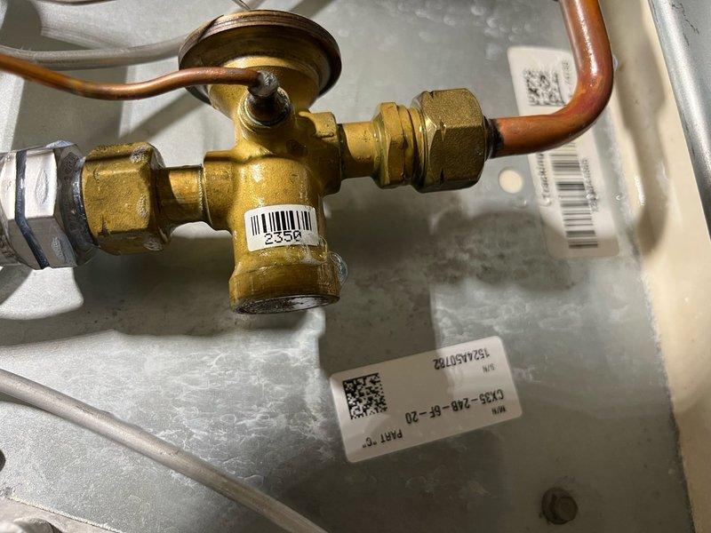 Responded to no cooling complaint on 2-3 year old Lennox central air system. Upon arrival, confirmed system was blowing warm air with no cooling capacity. Previous service history indicated refrigerant had been added along with UV dye approximately one year prior to identify leak source. 

Conducted thorough leak inspection of evaporator coil assembly. Observed UV dye splatter present inside ductwork and on evaporator coil panel. Noted thermostatic expansion valve (TXV) exhibited excessive oil accumulation on exterior surface. Applied soap bubble solution to TXV assembly while system was operating under pressure. Successfully isolated active refrigerant leak at TXV body housing. 

Documented findings with photographs of outdoor condensing unit and evaporator coil components including TXV valve assembly. Explained diagnostic findings to homeowner and demonstrated leak location at evaporator coil. Advised that warranty coverage and parts availability would need verification before procee