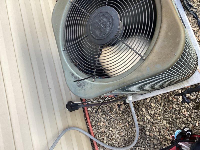 Responded to no cooling complaint on aging residential air conditioning system. Upon arrival, discovered outdoor condenser fan motor not operating. Investigation revealed wiring had dislodged from securing sleeve and became entangled around fan motor shaft, preventing rotation. Freed wiring from motor shaft and properly re-secured all wires away from moving components, restoring fan operation and system cooling capability.

During diagnostic evaluation, identified multiple components showing signs of deterioration and impending failure. Condenser fan motor exhibited reduced RPM, excessive heat generation, and potential bearing damage from wire entanglement incident. Contactor measured low resistance at approximately 10 ohms with visible pitting on contact surfaces, indicating electrical degradation. Compressor demonstrated labored startup with abnormal sound characteristics, suggesting mechanical wear consistent with system age.

Documented findings with photographic evidence showing o