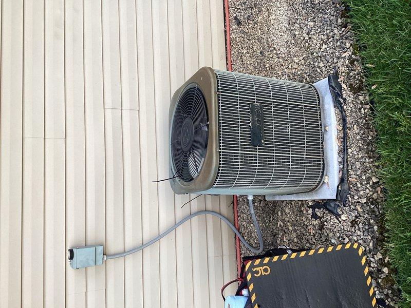 Responded to no cooling complaint on aging residential air conditioning system. Upon arrival, discovered outdoor condenser fan motor not operating. Investigation revealed wiring had dislodged from securing sleeve and became entangled around fan motor shaft, preventing rotation. Freed wiring from motor shaft and properly re-secured all wires away from moving components, restoring fan operation and system cooling capability.

During diagnostic evaluation, identified multiple components showing signs of deterioration and impending failure. Condenser fan motor exhibited reduced RPM, excessive heat generation, and potential bearing damage from wire entanglement incident. Contactor measured low resistance at approximately 10 ohms with visible pitting on contact surfaces, indicating electrical degradation. Compressor demonstrated labored startup with abnormal sound characteristics, suggesting mechanical wear consistent with system age.

Documented findings with photographic evidence showing o