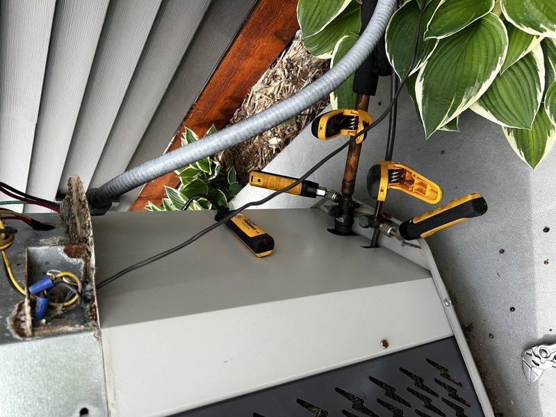Responded to no cooling complaint on 19-year-old air conditioning system. Upon arrival, verified thermostat call for cooling and inspected indoor unit. Found air filter in acceptable condition and tested blower motor capacitor, which measured 30% below rated specifications. Proceeded to outdoor condensing unit and connected refrigerant gauges to service ports. Diagnostic testing revealed critically low refrigerant charge with near-zero suction pressure readings. Visual inspection of outdoor coil showed significant dirt and debris accumulation on condenser fins. Due to system age and HCFC-22 refrigerant type, recommended customer consultation with service advisor regarding repair versus replacement options, as company policy does not support recharging legacy refrigerant systems.