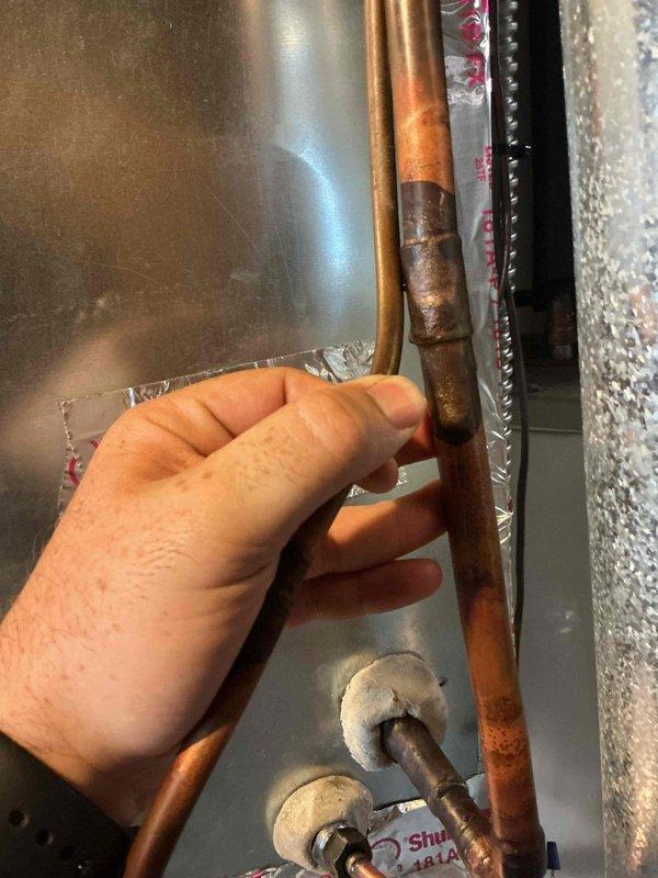 Responded to no cooling complaint on 7-year-old Goodman air conditioning system. Upon arrival, found warm air discharge from supply vents. Discovered evaporator coil frozen solid. Thawed coil and performed system diagnostics, revealing refrigerant charge 2-3 pounds low, indicating active leak in system. Visual inspection identified oily residue on refrigerant lineset near furnace connection point, though exact leak source could not be definitively determined without further testing. Recommended recharging system with refrigerant, injecting UV dye, and scheduling follow-up visit to pinpoint leak location under operating conditions. Provided repair estimates and system replacement options for consideration.