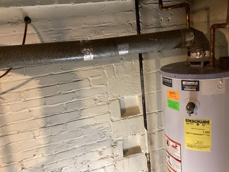 Responded to no hot water complaint and performed biannual plumbing maintenance inspection. Upon arrival, found pilot light extinguished on water heater located in basement utility area. Conducted thorough assessment of water heating system, including examination of gas valve assembly, thermostat controls, and all piping connections. Inspected age and condition of existing white cylindrical water heater unit with visible copper and black pipe fittings at top connections. 

During preventive maintenance evaluation, identified that water heater is no longer maintaining proper temperature settings despite pilot light status. Unit displays significant age-related degradation affecting heating performance and temperature consistency. Documented current condition with photographs showing EnergyGuide label, manufacturer specifications, control valve assembly, and overall installation configuration against painted concrete block wall. Noted standard plumbing connections including copper supply