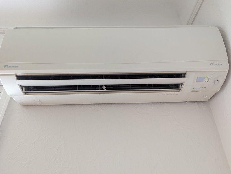 Responded to no cooling complaint on Daikin E-Series wall-mounted heat pump system. Upon inspection, found evaporator coil frozen with ice buildup, preventing proper heat exchange and airflow. Documented current system condition with photos of indoor head unit and outdoor condensing unit. System requires defrost cycle completion and follow-up diagnostic visit to determine root cause of freezing condition, which may include low refrigerant charge, restricted airflow, or faulty defrost controls.