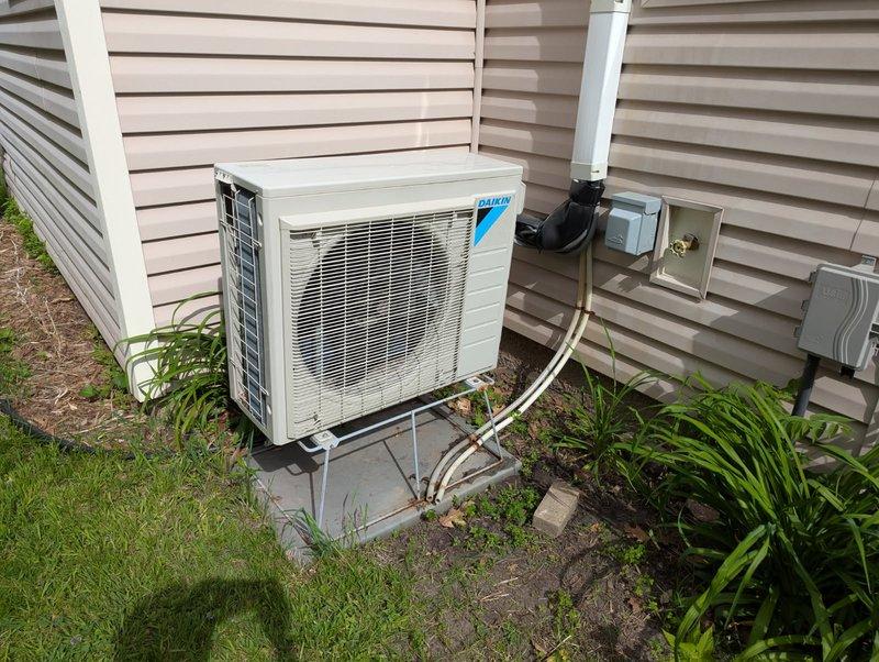 Responded to no cooling complaint on Daikin E-Series wall-mounted heat pump system. Upon inspection, found evaporator coil frozen with ice buildup, preventing proper heat exchange and airflow. Documented current system condition with photos of indoor head unit and outdoor condensing unit. System requires defrost cycle completion and follow-up diagnostic visit to determine root cause of freezing condition, which may include low refrigerant charge, restricted airflow, or faulty defrost controls.