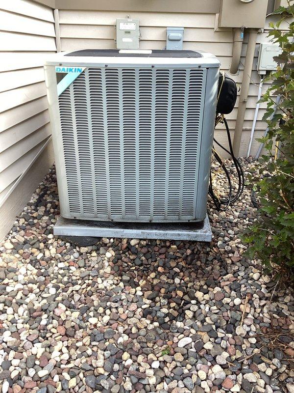 Responded to no cooling complaint on Daikin condensing unit with compressor and coil previously replaced last year. Found system completely flat with no refrigerant charge. Performed vacuum test and added refrigerant to diagnose compressor failure—compressor would not start and ohm testing revealed two of three windings showing no resistance, confirming internal compressor failure. Discovered burn marks on electrical disconnect box that were previously noted during last year's compressor replacement but not addressed. Recommend licensed electrician inspect and repair electrical disconnect prior to installing replacement compressor under warranty to prevent recurring failure.