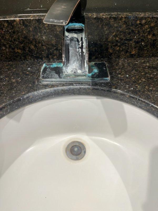 Installed customer-supplied waterfall-style lavatory faucet with glass spout and oil-rubbed bronze finish on bathroom vanity with granite countertop. Addressed clogged drain issue and completed minor drain repairs, including work on P-trap assembly and PVC drainage system beneath sink. Resolved slight leak in existing plumbing connections and ensured proper water flow through new faucet installation.
