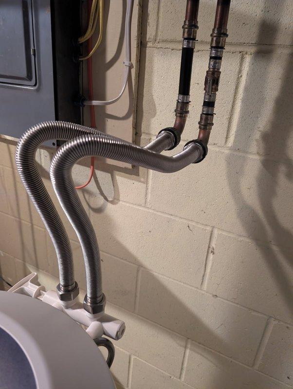 Responded to a burst pipe emergency where a ProPress fitting failed on the water supply line to the outdoor sprinkler system. Cut out the compromised section of copper piping and installed new pipe with proper fittings to restore water flow. Additionally, replaced temporary flexible supply lines to the water softener with permanent copper piping and shut-off valves, upgrading the installation to meet proper plumbing standards and eliminate the unreliable temporary connections.