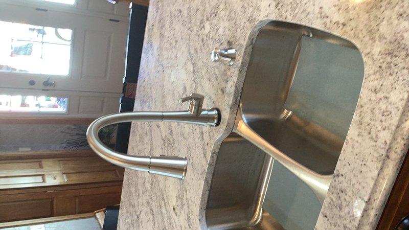 Completed kitchen plumbing hookup including installation of new faucet on double-basin stainless steel sink. Connected water supply lines, installed drain assembly with P-trap configuration, and verified proper operation of all fixtures. All connections tested and confirmed leak-free with full functionality restored.
