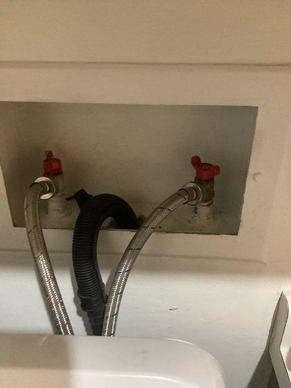 Responded to a service call for malfunctioning washing machine supply valves following washer/dryer installation. Upon inspection, found both hot and cold water shut-off valves were broken and inoperable, preventing proper water flow control to the washing machine. Successfully replaced both deteriorated valves with new quarter-turn shut-off valves featuring red handles for easy identification and operation. Installed new braided stainless steel supply lines to ensure reliable connections between the wall-mounted valves and washing machine. Tested all connections for leaks and verified proper shut-off functionality of both hot and cold water valves. System is now fully operational with secure, leak-free connections.