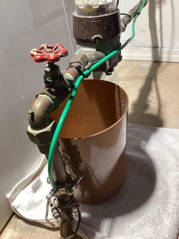 Responded to a significant water leak at the main water shut-off valve that was filling a bucket every few hours. Upon inspection, diagnosed the issue as a failed packing nut on the city-side main valve. The valve had been previously serviced with a temporary tightening repair, but deterioration had progressed to the point of requiring more extensive intervention. Documented the condition of the aged plumbing assembly, including the corroded valve with red wheel handle and associated brass fittings showing significant oxidation and patina. Presented the customer with comprehensive options for both complete valve replacement and rebuilding the existing valve assembly to restore proper function and eliminate the active leak.