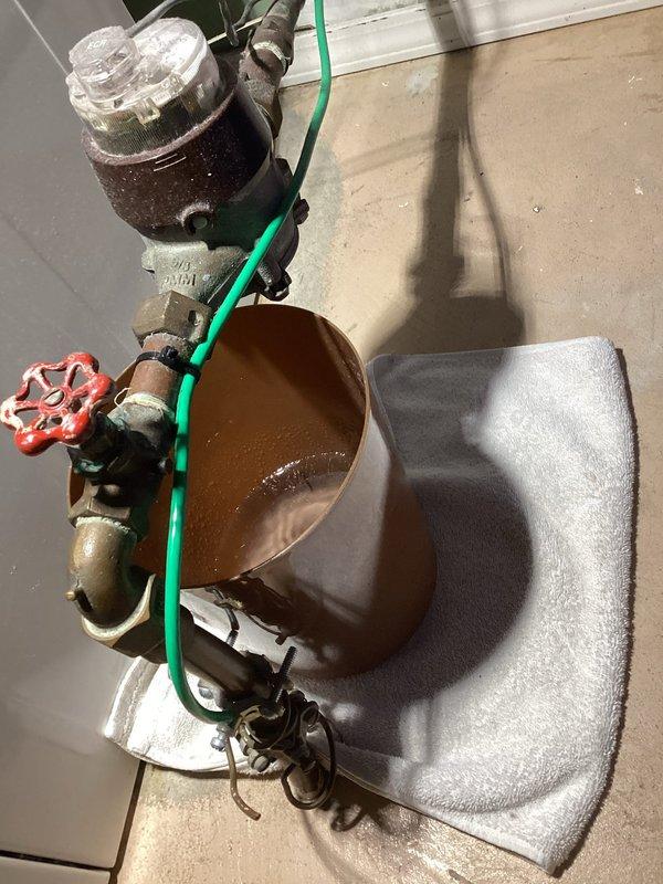 Responded to a significant water leak at the main water shut-off valve that was filling a bucket every few hours. Upon inspection, diagnosed the issue as a failed packing nut on the city-side main valve. The valve had been previously serviced with a temporary tightening repair, but deterioration had progressed to the point of requiring more extensive intervention. Documented the condition of the aged plumbing assembly, including the corroded valve with red wheel handle and associated brass fittings showing significant oxidation and patina. Presented the customer with comprehensive options for both complete valve replacement and rebuilding the existing valve assembly to restore proper function and eliminate the active leak.
