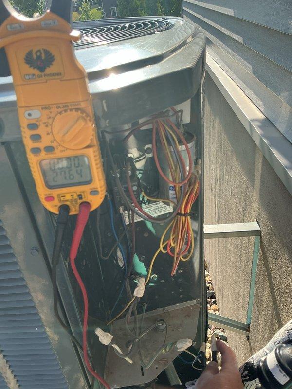 Responded to no cooling complaint on 11-year-old air conditioning system. Upon arrival, found unit not running due to low pressure safety switch activation. Bypassed low pressure switch to perform diagnostic testing of refrigerant levels. Encountered seized low side service port locking cap that could not be removed; obtained pressure readings from high side service port only. Readings confirmed system is significantly low on refrigerant charge. Identified refrigerant type as obsolete R-22, which is no longer manufactured and has limited availability at premium cost. Used digital multimeter to verify electrical components and capacitor operation within acceptable parameters. Accessed outdoor condenser unit and inspected internal wiring, contactor, and run capacitor - all components functioning properly when power supplied. Confirmed compressor attempts to run when low pressure safety is bypassed, indicating mechanical components operational but insufficient refrigerant charge preventin