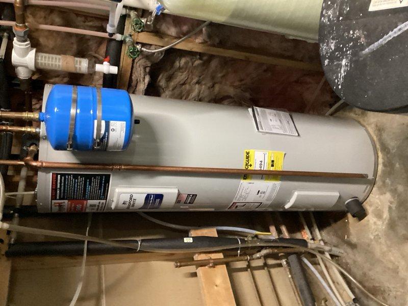 Responded to water quality issue related to fish odor in residential water supply. Placed acid neutralizer system into bypass mode to eliminate odor problem. System had been actively treating water but was identified as the source of the undesirable smell. Documented equipment configuration including water heater, expansion tank, and water treatment components in mechanical room.