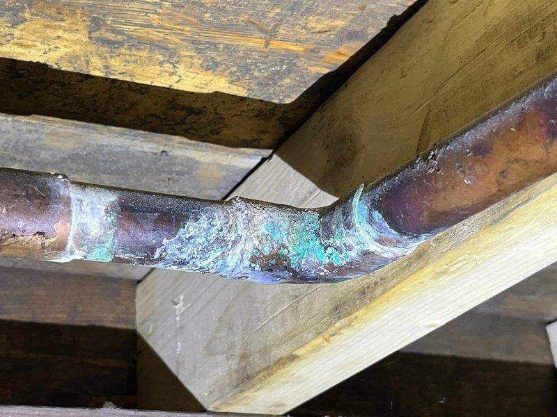 Responded to a slow dripping leak at a copper pipe elbow in the well room that had been occurring for several days. Upon inspection, identified a failed sweat joint at a 90-degree elbow showing extensive corrosion and verdigris buildup. Replaced the compromised house ball valve and repaired piping from the valve up through the tee connection, installing new copper lines to eliminate the leak and ensure proper water flow to the residence.