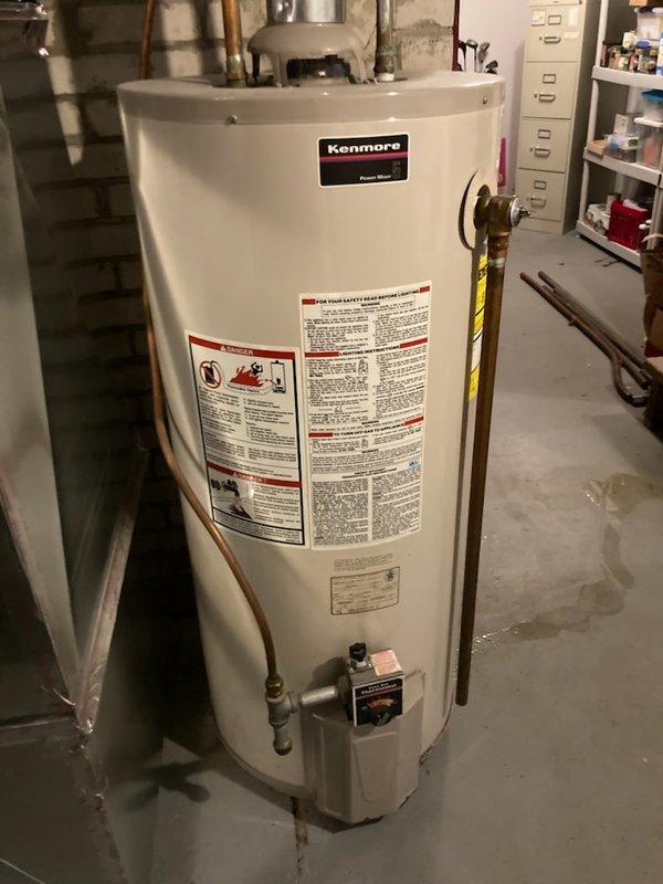 Responded to service call for 23-year-old conventional tank water heater experiencing leak from bottom of unit. Upon inspection, confirmed active water seepage at base of Kenmore Power Miser tank-style water heater in basement utility area. Due to age of unit and location of leak, determined tank failure requiring full replacement rather than repair. Coordinated replacement installation, shut off water supply and gas connections, drained existing unit, and removed failed water heater from service area. Prepared site for new equipment installation with proper clearances and access to existing copper supply lines, gas piping, and venting infrastructure.