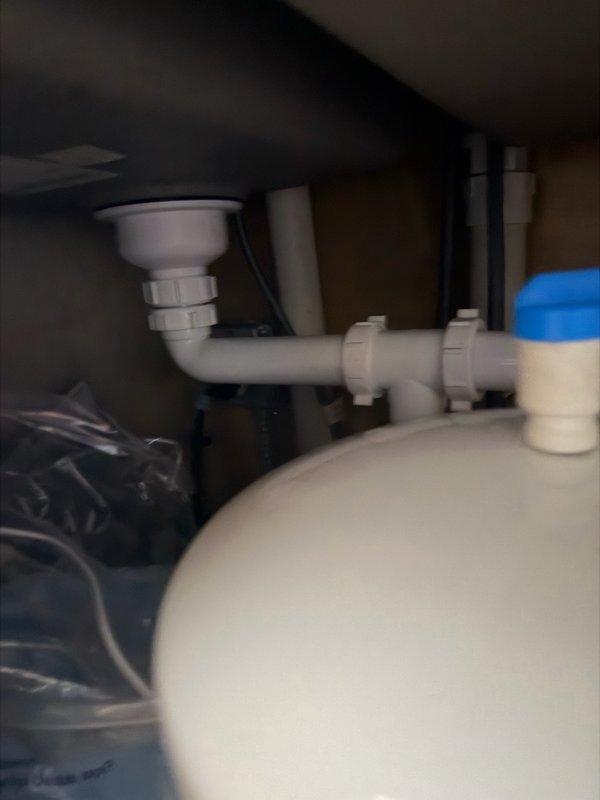 Responded to service call for reverse osmosis system producing excessive noise after use. Upon inspection, identified air gap hissing loudly for approximately 10 minutes following water dispensing from RO unit. Diagnosed issue as improper drainage causing air gap overflow and noise disturbance. Installed check valve on RO drain line to prevent backflow and eliminate hissing sound from air gap. Tested system operation and verified noise issue resolved. System now functioning properly with normal quiet operation after water use.