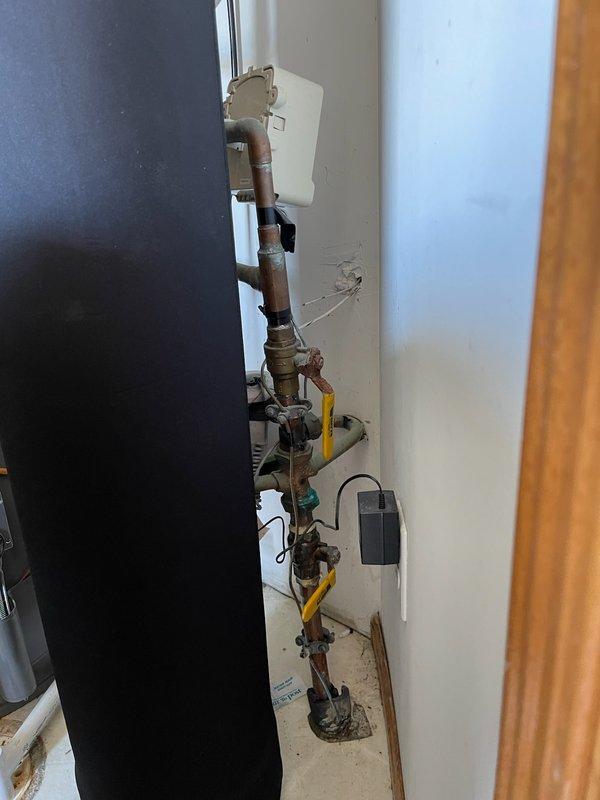 Responded to water leak at main meter assembly. Upon inspection, identified active leak at meter horn connection with deteriorated gasket. Multiple valves in the assembly showed significant corrosion and rust buildup, indicating age and exposure to moisture. Replaced failed gasket at meter horn to resolve leak. Documented condition of corroded brass fittings and yellow-handled shut-off valves throughout vertical pipe assembly for future maintenance reference.