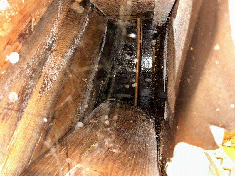 Responded to emergency water leak affecting kitchen ceiling with active dripping through sheetrock and visible sagging. Upon investigation, identified failed drain pipe connection serving upstairs kitchen sink as source of water intrusion into downstairs ceiling cavity. Accessed affected area through ceiling opening to assess extent of damage. Documentation revealed significant moisture damage to wooden framing members with visible mold growth and dark staining on joists and beams surrounding the leak point. Observed copper drain piping with compromised connection causing water discharge during sink usage. Repaired leaking drain pipe connection to restore proper drainage function and eliminate active water infiltration. Advised property owner of moisture damage to structural framing and presence of mold contamination requiring remediation by qualified contractor. Recommended ceiling repair and replacement of affected sheetrock following complete drying of framing members. Verified repa