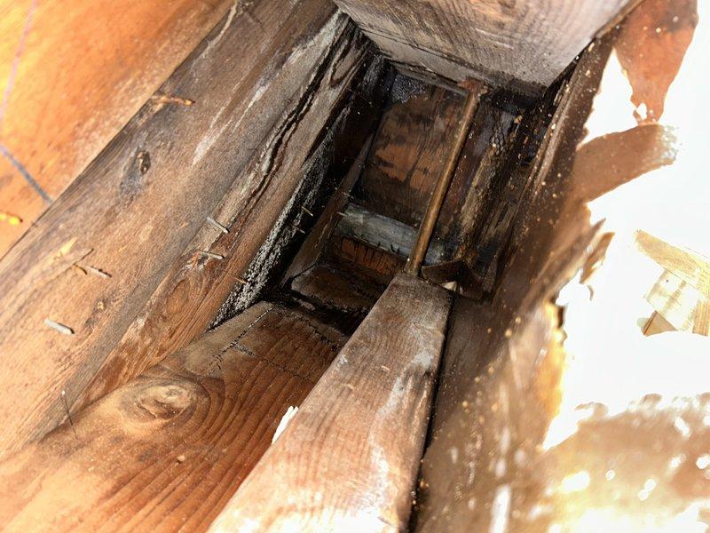 Responded to emergency water leak affecting kitchen ceiling with active dripping through sheetrock and visible sagging. Upon investigation, identified failed drain pipe connection serving upstairs kitchen sink as source of water intrusion into downstairs ceiling cavity. Accessed affected area through ceiling opening to assess extent of damage. Documentation revealed significant moisture damage to wooden framing members with visible mold growth and dark staining on joists and beams surrounding the leak point. Observed copper drain piping with compromised connection causing water discharge during sink usage. Repaired leaking drain pipe connection to restore proper drainage function and eliminate active water infiltration. Advised property owner of moisture damage to structural framing and presence of mold contamination requiring remediation by qualified contractor. Recommended ceiling repair and replacement of affected sheetrock following complete drying of framing members. Verified repa