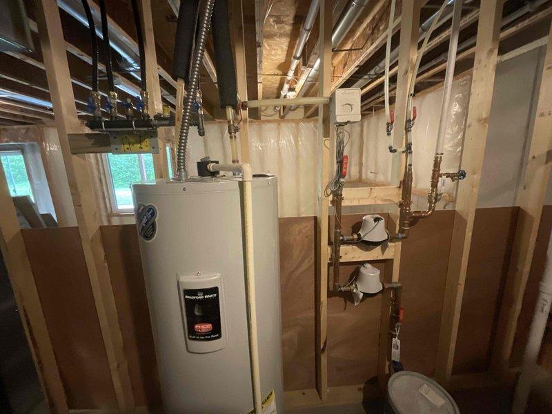 Responded to service call for 4-year-old water heater leaking from bottom in unfinished basement utility area. Upon arrival, identified unit as electric tanked water heater with active leak at base, indicating internal tank failure. Assessed existing plumbing connections including copper supply lines, shut-off valves, and discharge piping. Documented equipment condition and surrounding installation area with exposed framing and concrete floor. Coordinated arrival time with customer per scheduling requirements.