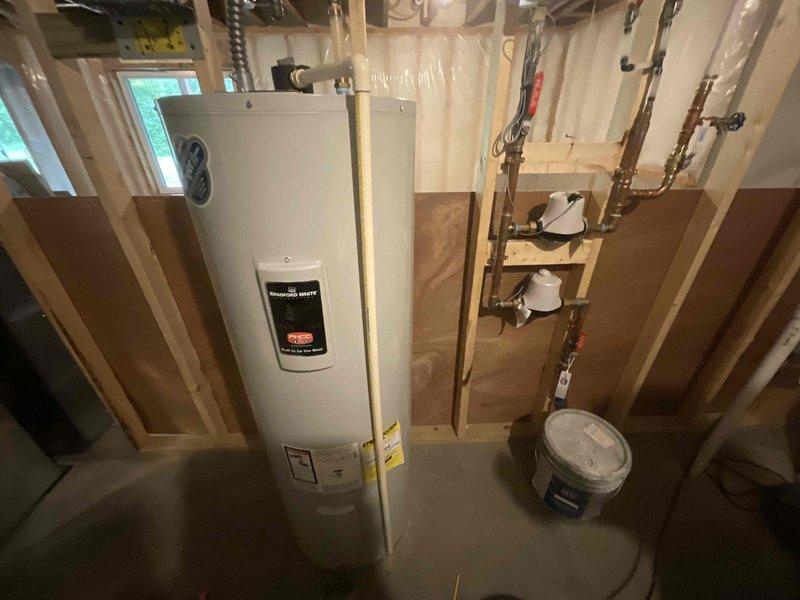 Responded to service call for 4-year-old water heater leaking from bottom in unfinished basement utility area. Upon arrival, identified unit as electric tanked water heater with active leak at base, indicating internal tank failure. Assessed existing plumbing connections including copper supply lines, shut-off valves, and discharge piping. Documented equipment condition and surrounding installation area with exposed framing and concrete floor. Coordinated arrival time with customer per scheduling requirements.