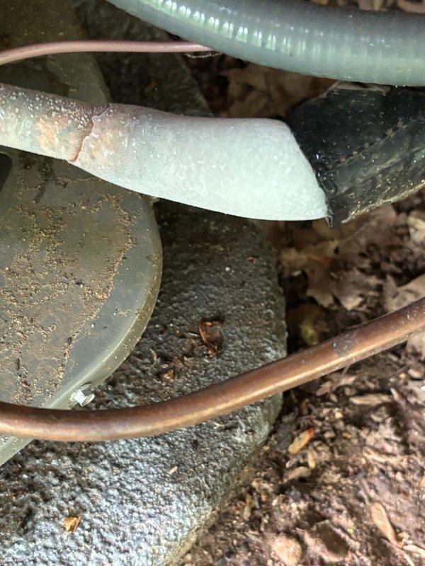Responded to no cooling condition on 1-year-old system experiencing repeat evaporator coil freeze-up. Upon arrival, found evaporator coil completely encased in ice with frost extending along suction line to outdoor compressor unit. Detected refrigerant leaks within indoor unit but unable to perform comprehensive leak detection due to extensive ice accumulation on coil assembly. Documented frozen coil condition and suction line with photographs showing heavy frost buildup on refrigerant lines in crawlspace and complete ice encasement of evaporator coil within air handler cabinet. System requires follow-up visit after coil thaw to conduct thorough leak detection and determine if failure is related to thermostatic expansion valve malfunction or evaporator coil leak.