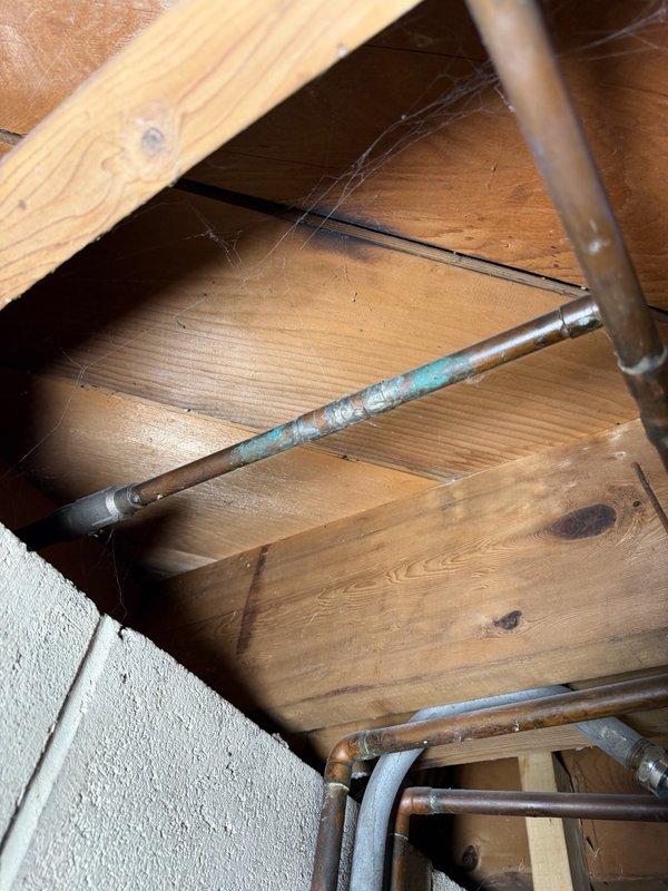 Completed comprehensive plumbing inspection as part of family rewards program. Accessed attic and crawlspace areas to assess plumbing system condition, documenting copper supply lines with visible oxidation and verdigris patina formation. Identified advanced corrosion on metal pipe fittings in crawlspace, with heavy blue-green copper corrosion indicating potential moisture exposure and age-related deterioration requiring monitoring or future replacement consideration.