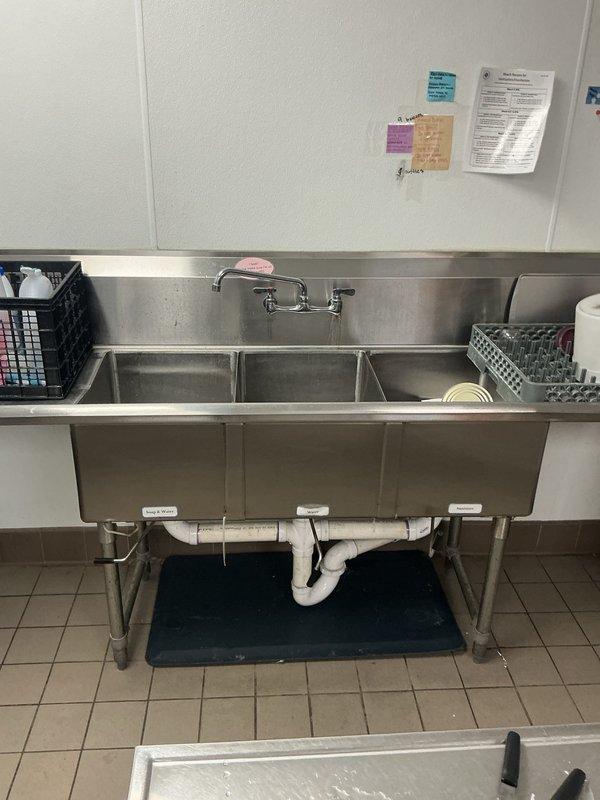 Responded to commercial kitchen for reported draining issues on three-compartment stainless steel sink. Upon inspection, identified that drain gaskets in two compartments were not properly seated, causing one basin to fail to hold water and another to drain excessively despite stopper being engaged. Adjusted and reseated gaskets in both affected compartments to restore proper function. Documented current condition and provided bid for future replacement of drain assembly components.