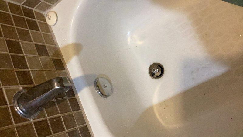 Responded to water leak complaint originating from bathtub drain assembly. Upon arrival, identified wet spot in ceiling below bathroom with access hole already cut for inspection. Accessed plumbing system from stairwell wall cavity, eliminating need for tile removal in bathroom. Inspected tub drain and overflow assembly through wall access point and confirmed active leak at tub drain connection. Removed existing defective tub drain fitting and installed new chrome tub drain assembly with proper sealing and gaskets. Tested drainage system for leaks and verified proper water flow and complete seal at all connection points. Documented existing conditions and completed repairs through photographic record.
