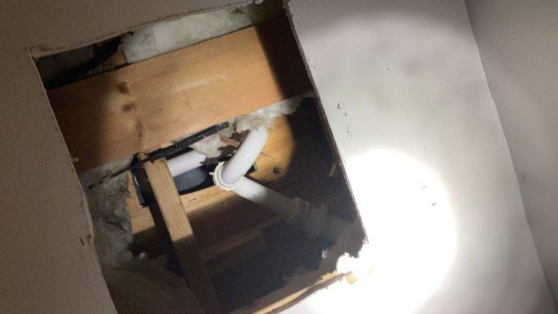 Responded to water leak complaint originating from bathtub drain assembly. Upon arrival, identified wet spot in ceiling below bathroom with access hole already cut for inspection. Accessed plumbing system from stairwell wall cavity, eliminating need for tile removal in bathroom. Inspected tub drain and overflow assembly through wall access point and confirmed active leak at tub drain connection. Removed existing defective tub drain fitting and installed new chrome tub drain assembly with proper sealing and gaskets. Tested drainage system for leaks and verified proper water flow and complete seal at all connection points. Documented existing conditions and completed repairs through photographic record.
