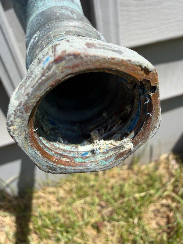 Responded to exterior sprinkler system leak at residential property. Upon inspection, identified failed pressure vacuum breaker (PVB) with cracked drain down port inside the fitting, causing visible water discharge. Removed compromised section of irrigation piping and installed replacement pipe segment. Installed drain down plugs to properly seal the irrigation system and prevent future leakage. System tested and confirmed operational with no active leaks following repair completion.