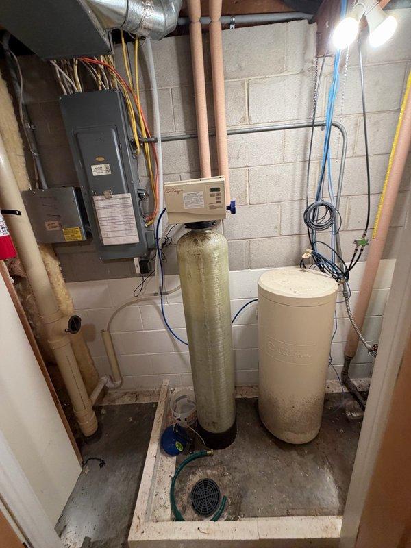 Performed diagnostic evaluation of multiple plumbing issues throughout the residence. Inspected non-functioning Culligan water softener system in basement to assess condition and determine serviceability. Evaluated kitchen double-handle faucet with hot water side leaking due to backed-out threading and assessed cold water side for potential issues. Examined downstairs faucet requiring repair after components separated. Inspected two upstairs tub/shower drains to determine whether rebuild or replacement would be necessary. Assessed water filter connected to master bathroom faucet for replacement needs. Documented equipment conditions including water softener, pressure tank, and associated plumbing connections. Recommended service agreement for comprehensive repairs and ongoing maintenance of identified issues.