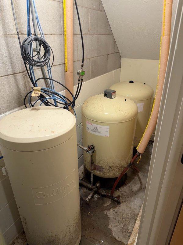 Performed diagnostic evaluation of multiple plumbing issues throughout the residence. Inspected non-functioning Culligan water softener system in basement to assess condition and determine serviceability. Evaluated kitchen double-handle faucet with hot water side leaking due to backed-out threading and assessed cold water side for potential issues. Examined downstairs faucet requiring repair after components separated. Inspected two upstairs tub/shower drains to determine whether rebuild or replacement would be necessary. Assessed water filter connected to master bathroom faucet for replacement needs. Documented equipment conditions including water softener, pressure tank, and associated plumbing connections. Recommended service agreement for comprehensive repairs and ongoing maintenance of identified issues.