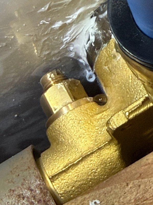 Responded to a water leak located behind the shower wall. Upon investigation, identified a loose brass compression fitting at the shower head connection point on the shower valve assembly. Opened the shower wall to access the affected plumbing components, tightened the leaking fitting, and verified proper seal to eliminate water discharge. Observed water pooling on the concrete floor beneath the valve body, confirming active leak prior to repair. Successfully resolved the leak issue and restored proper function to the shower system.