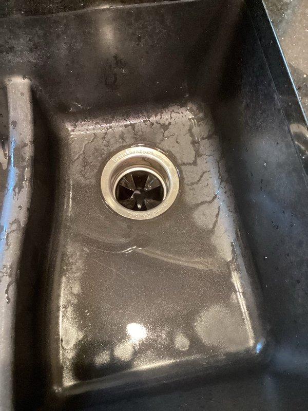 Responded to service call for non-functioning garbage disposal that was initially making a buzzing noise before ceasing all operation. Upon inspection, used allen wrench to manually rotate the disposal mechanism to check for jammed impeller. Reset the disposal unit using the reset button located on the bottom of the unit. Assessed disposal functionality and determined unit was operational after reset procedure. Documented equipment condition with photographs showing InSinkErator disposal unit installation under sink and drain opening condition.