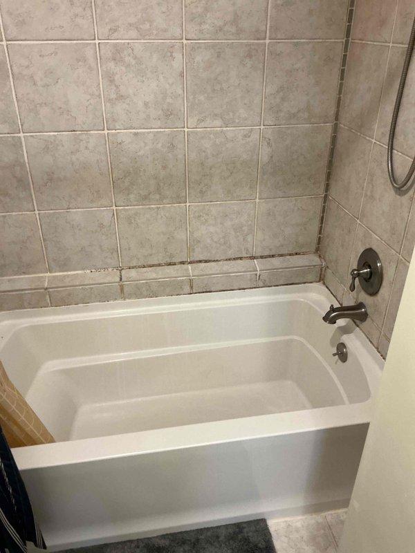 Responded to water leak complaint originating from master bathroom shower/tub area with visible damage to garage ceiling below. Upon inspection, identified deteriorated grout lines and caulking around tub-to-tile transition points showing significant discoloration and moisture infiltration. Observed compromised waterproofing at shower fixture penetrations and along bathtub perimeter where tile meets tub surface. Documented existing conditions with photographs showing aged grout, possible mildew presence, and darkened caulk joints indicating chronic water seepage. Due to extent of water damage and need for comprehensive moisture remediation in affected ceiling area, referred customer to restoration specialist for proper drying, mold assessment, and structural repair before plumbing repairs can be completed.