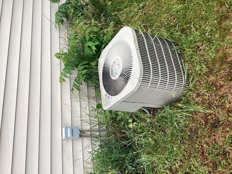 Responded to no cooling complaint on 20-year-old R22 system with reported buzzing at outdoor unit and non-operational fan. Upon arrival, cycled system and confirmed outdoor unit operational. Identified severely restricted air filter causing reduced airflow and only 10-degree temperature split across evaporator coil even after filter replacement. Inspected outdoor condenser unit and found heavy dirt accumulation on coil, though all electrical components tested within manufacturer specifications. Detected low refrigerant charge on R22 system. Found evaporator coil significantly plugged with debris and active refrigerant leak at coil location causing moisture damage on top of furnace cabinet. Documented equipment condition with photographs showing outdoor condenser placement and indoor furnace/evaporator assembly. Reviewed system age, overall condition, and repair needs with homeowner, discussing both immediate concerns and anticipated future failures given equipment age and R22 phase-out