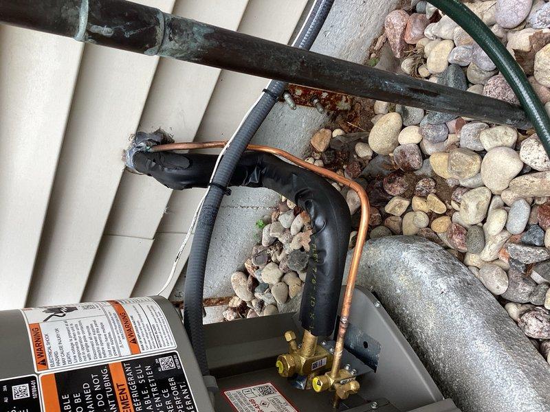 Responded to warranty call for noisy AC system with sound resonating inside residence. Replaced condensing unit as preventative measure, though original unit appeared to operate normally with standard sound levels at exterior location. Installed sound-deadening 90-degree elbows on refrigerant line set at outdoor installation point, which reduced interior noise resonance but did not fully resolve the issue. System remains operational but requires follow-up service to address persistent noise transmission into living space. Recommended solution involves installing new refrigerant line set routed through unfinished area to eliminate vibration transfer and sound resonance into occupied spaces.