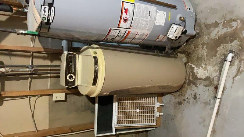 Completed comprehensive plumbing inspection of residential utility room containing water heater, water softener system, and associated piping. Documented existing equipment configuration including A.O. Smith water heater, water treatment system with control head, copper supply lines, pressure relief valve assembly, and PVC drainage piping. Noted extensive water staining and mineral deposits on concrete floor indicating previous moisture issues requiring monitoring.
