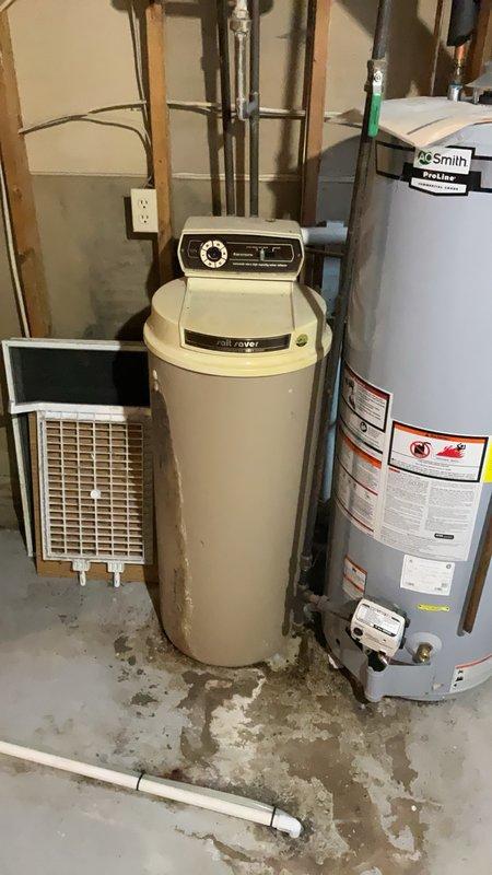 Completed comprehensive plumbing inspection of residential utility room containing water heater, water softener system, and associated piping. Documented existing equipment configuration including A.O. Smith water heater, water treatment system with control head, copper supply lines, pressure relief valve assembly, and PVC drainage piping. Noted extensive water staining and mineral deposits on concrete floor indicating previous moisture issues requiring monitoring.