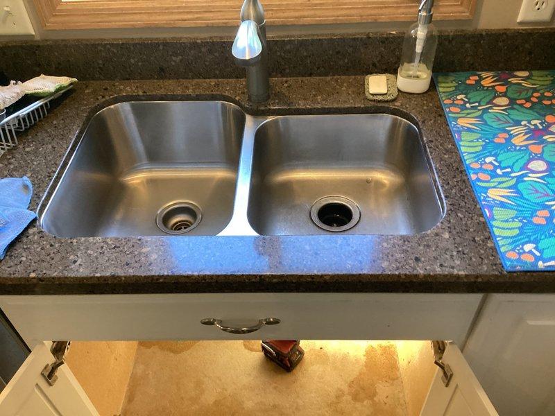 Responded to service call for leaking outdoor hose bibb and kitchen plumbing issues. Replaced faulty washer component on exterior spigot, resolving the leak at the hose bib connection point. Completed full replacement of kitchen faucet at double-basin undermount sink. Documented completed installations with photographs showing properly functioning exterior spigot with attached garden hose and updated kitchen faucet fixture.