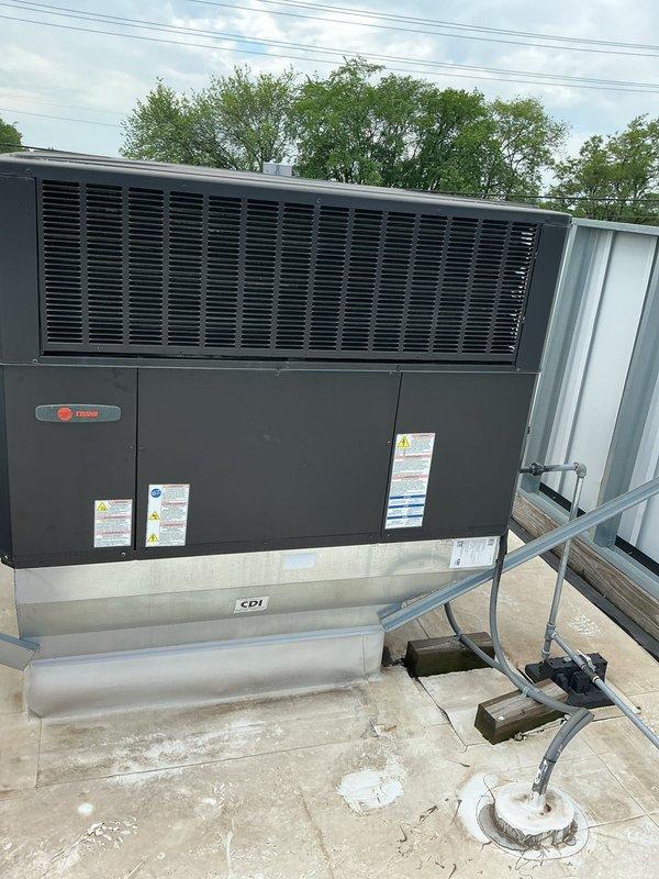 Responded to service call for commercial Trane rooftop unit RTU-6 with weak airflow complaint. Performed preventative maintenance inspection on 10+ year old unit, documented equipment condition with photographs showing multiple RTU installations on commercial facility rooftop. Unit operational at time of service with all safety labels and specifications visible and intact.