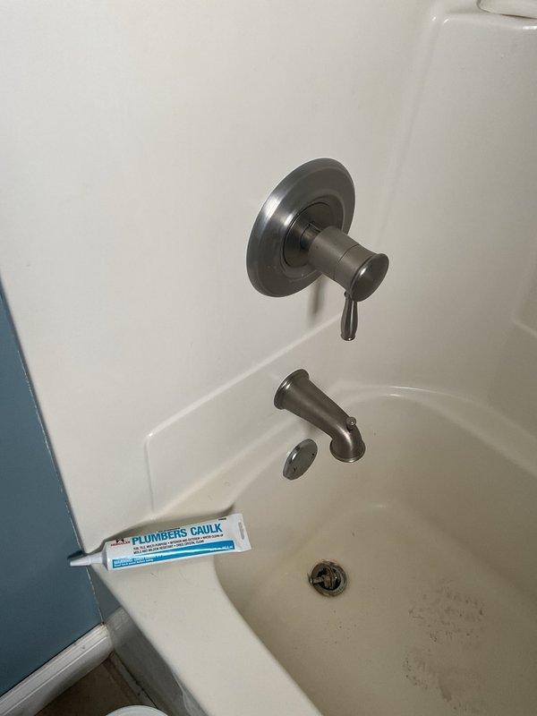 Responded to water leak originating from bathtub/shower area with visible water damage on ceiling below. Upon inspection, identified failed silicone seal around tub spout as source of leak. Removed deteriorated caulking and resealed tub spout with fresh plumber's silicone to restore watertight seal and prevent further water intrusion.